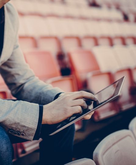 intro image man using mobile tablet in sports stadium